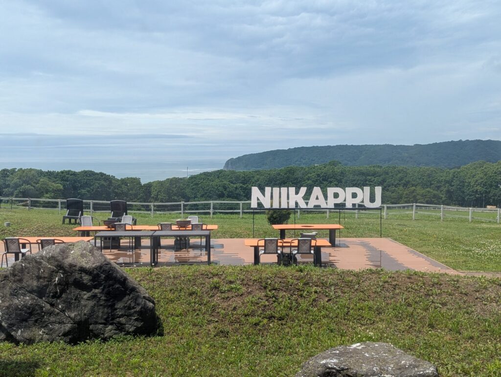 新冠温泉の屋外テラスとNIiKAPPUのサイン、遠くに見える海と山並み