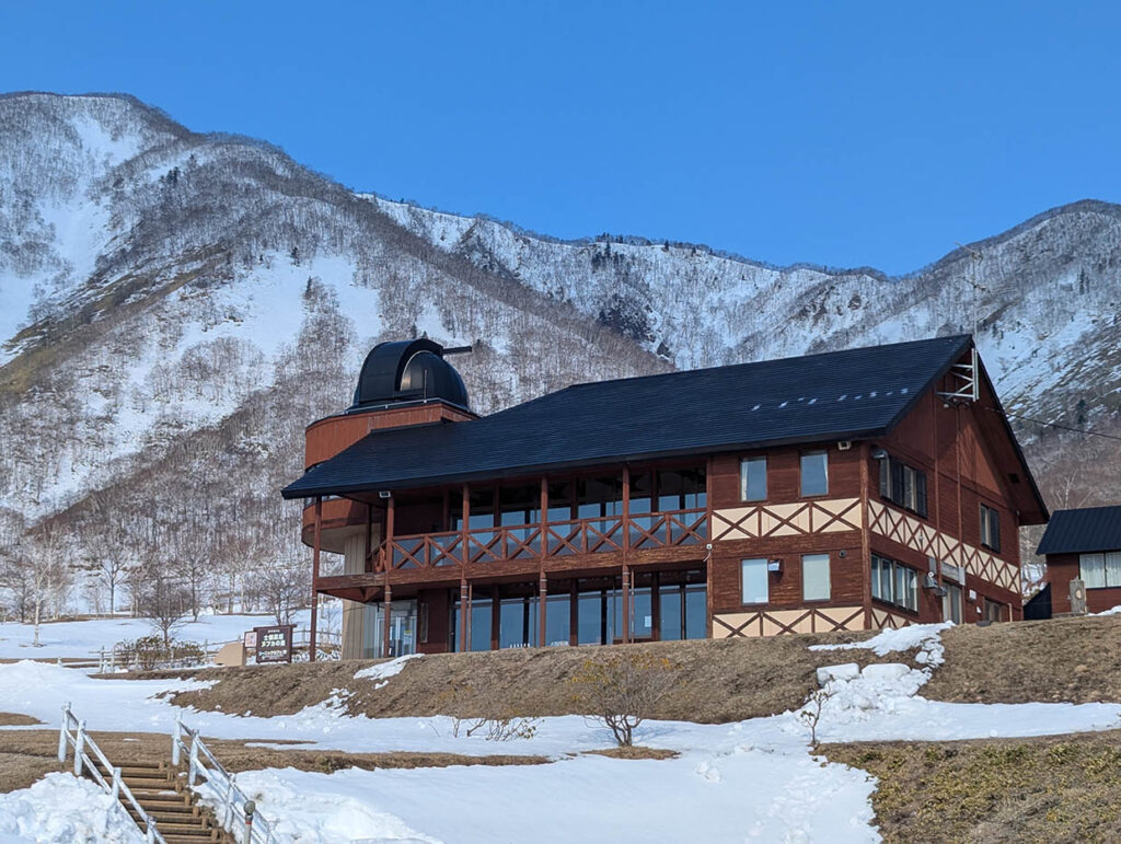 ヌプカの里の木造ロッジと背景にそびえる雪山