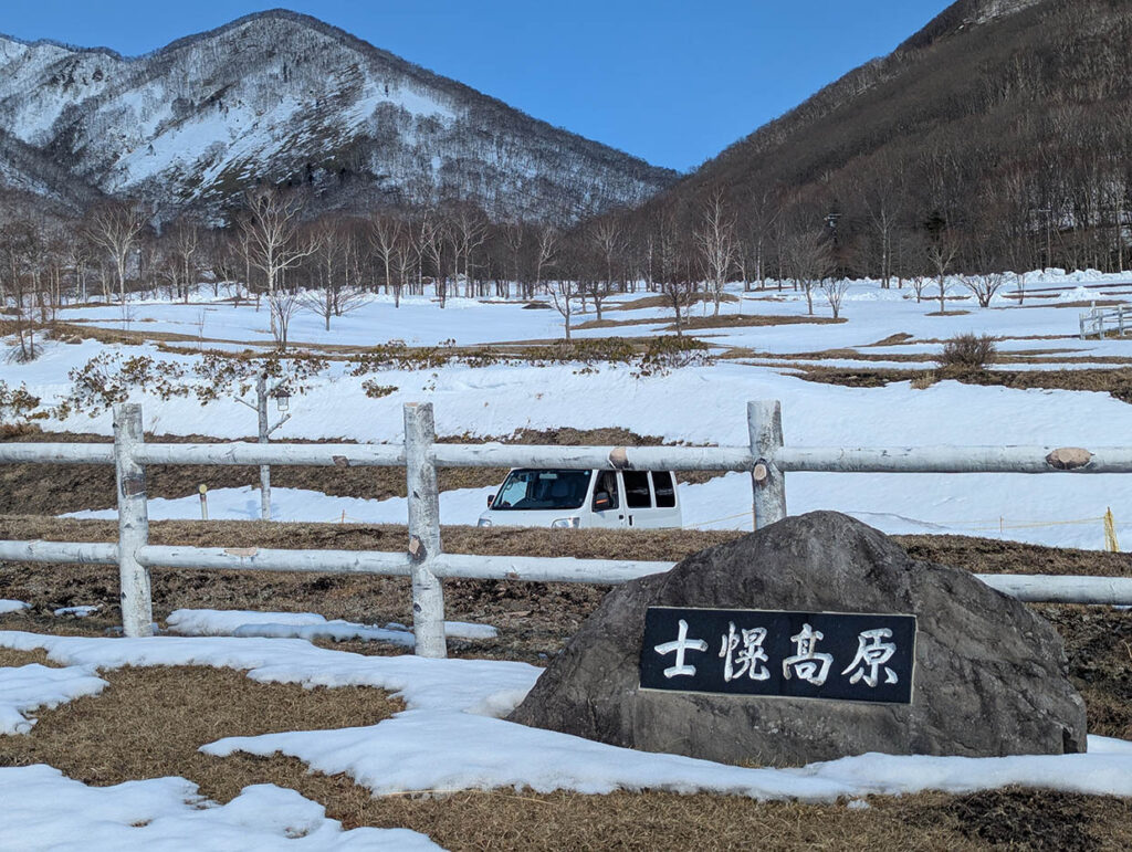 ヌプカの里の「士幌高原」の石碑と雪原、背景に軽バン