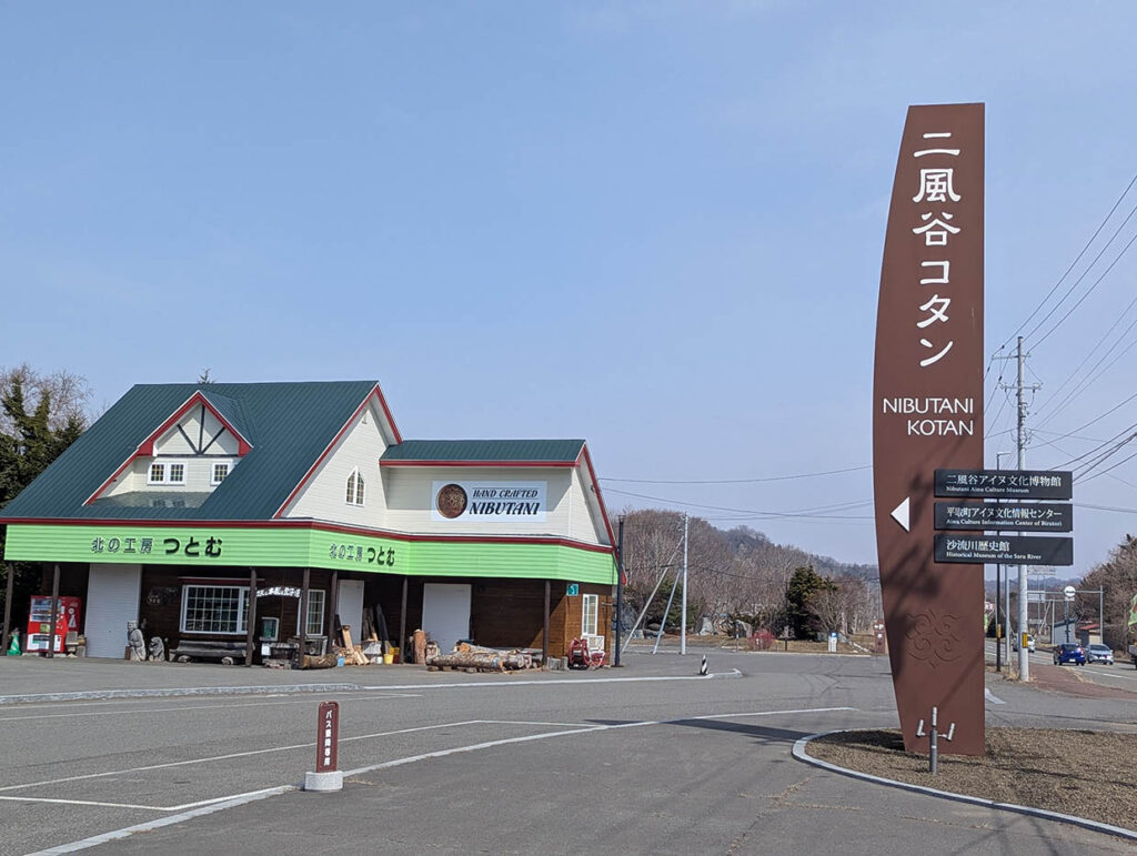 北海道平取町の二風谷コタン、アイヌ文化を紹介する案内看板と北の工房つとむの外観