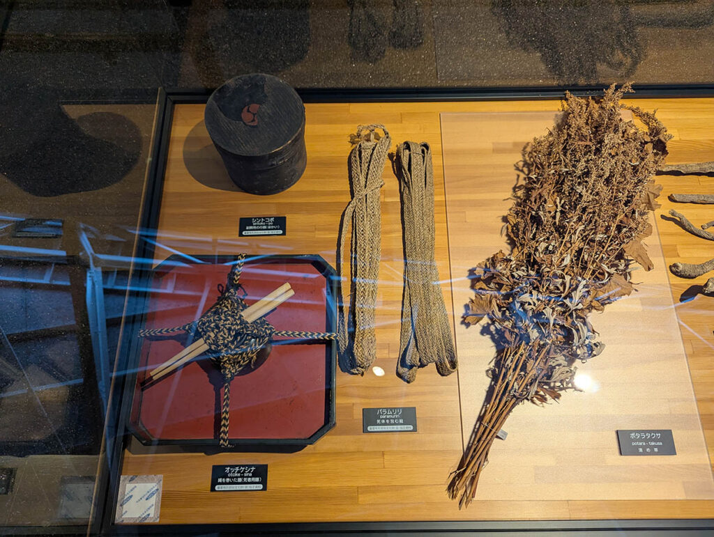 平取町立二風谷アイヌ文化博物館に展示されたアイヌの生活道具、植物や縄、木の容器などの資料