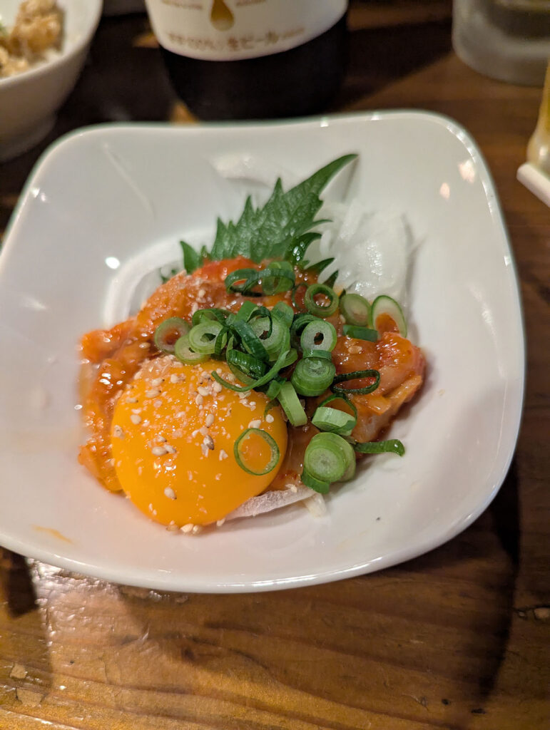 高松市の居酒屋で提供されたユッケ風刺身料理(卵黄とネギ、大葉添え)