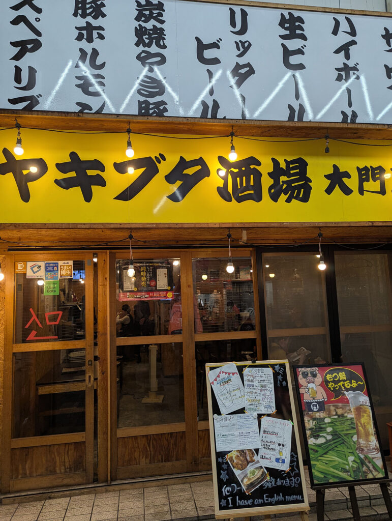 香川県高松市の居酒屋「ぶたにく酒場 大門屋」の夜の外観とメニュー看板