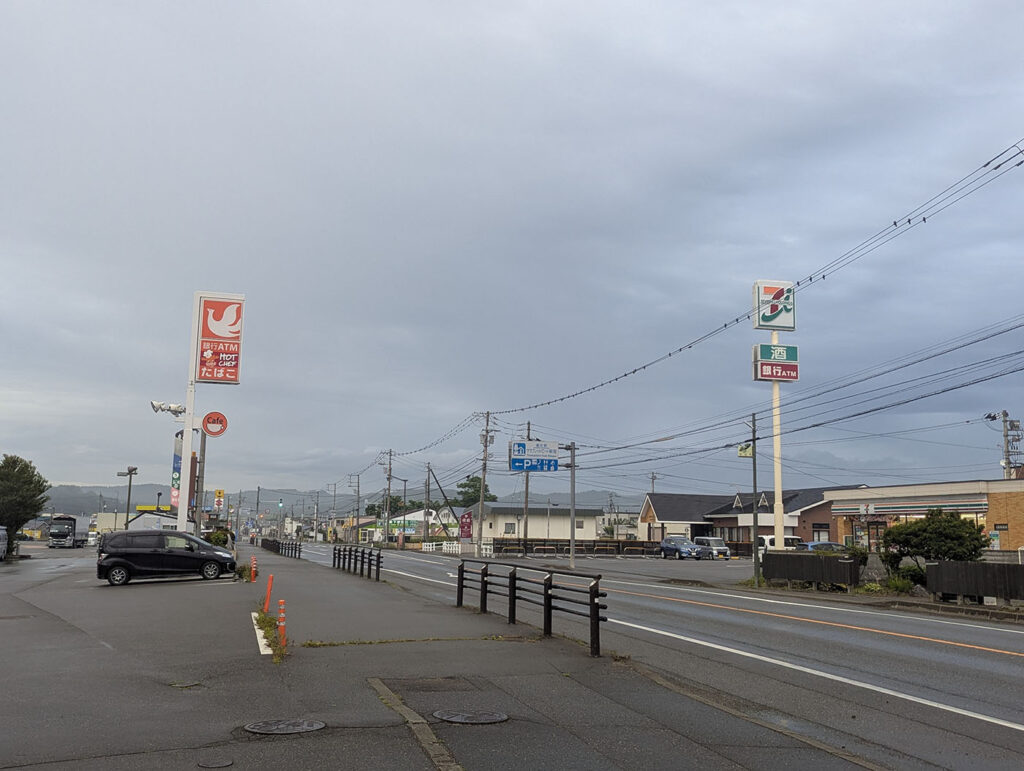 北海道新冠町の国道沿い風景。セイコーマートとセブンイレブンの看板が並び、広い空と郊外の街並みが広がる。