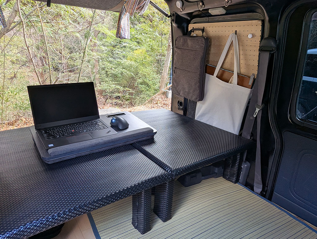 ハイゼットカーゴをフラット化した荷室にノートPCを置き、甲山の自然を背景にノマドワークする車中オフィス空間