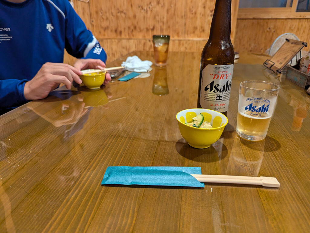 五三五の小瓶ビールとお通し。アサヒスーパードライの瓶と、胡瓜入りのお通しがテーブルに並んでいる。
