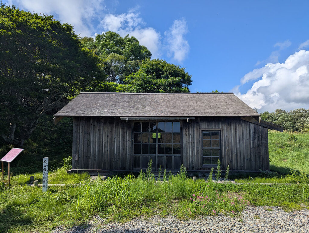 晩成社跡地に復元された依田勉三の住居。木造の素朴な建物が青空の下に静かに佇んでいる。