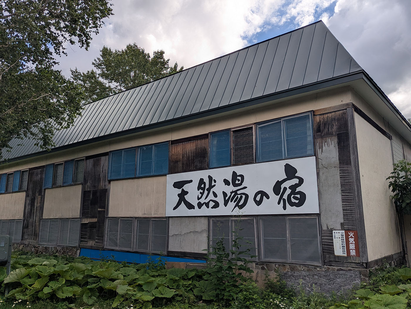 「天然湯の宿」の看板が残る山田温泉の旧宿舎。現在は営業しておらず、静かに時を止めている。