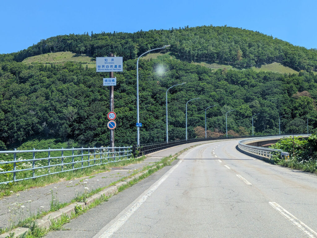 知床峠へ向かう国道334号線。緑豊かな山々と「知床 世界自然遺産」の標識が見える。