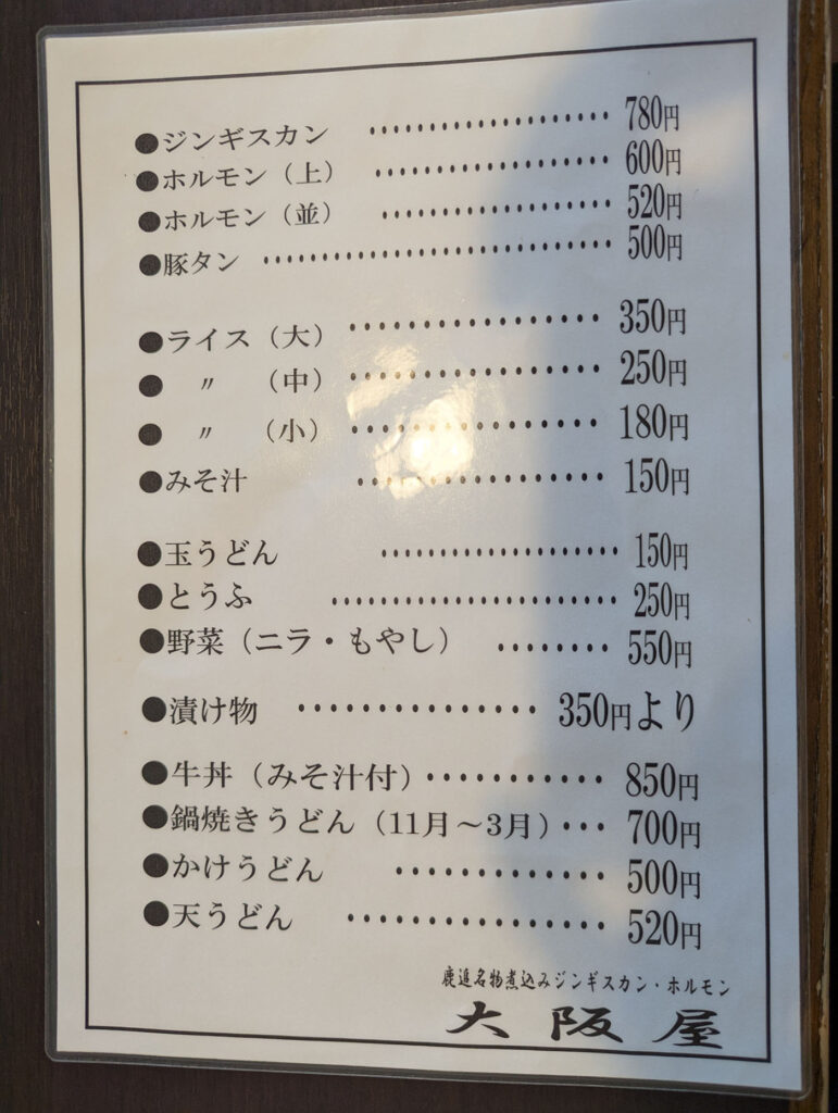 北海道鹿追町「大阪屋」のフードメニュー表。ジンギスカンやホルモン、豚タンに加え、うどんや牛丼などの定食系メニューも掲載されている。