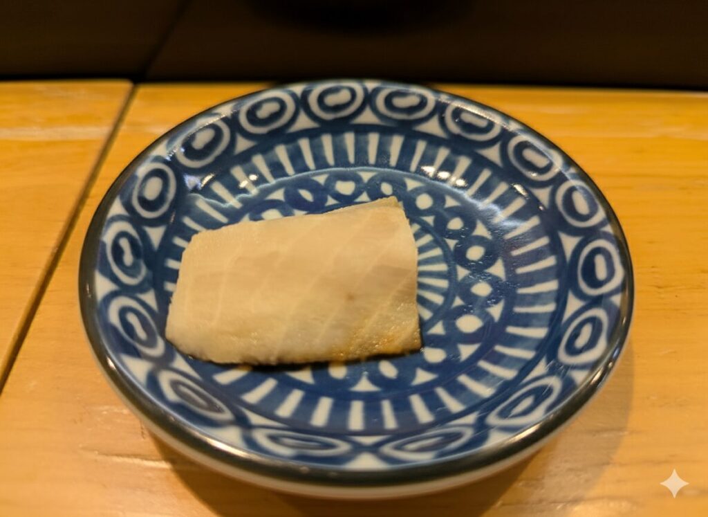 青い小皿に盛られたチョウザメのルイベ。白身がしっとりと光っている。