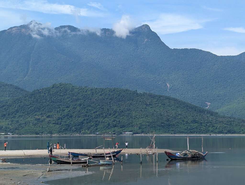 途中休憩で立ち寄ったランコー湾の静かな風景。青々とした山並みを背景に、小舟が穏やかな水面に浮かんでいる。