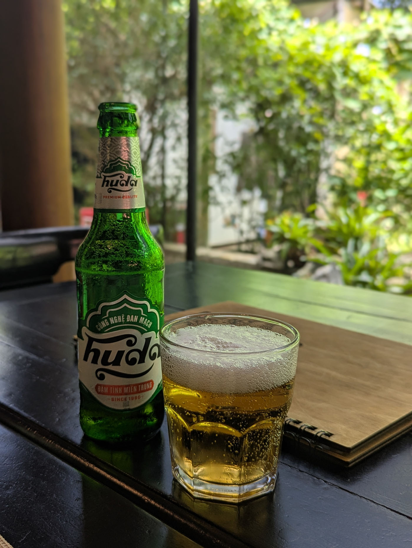 緑の瓶に入ったベトナムのローカルビール「フーダ」と、グラスに注がれた黄金色のビール